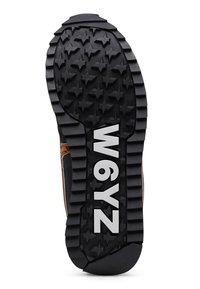 Černá gumová podrážka s hvězdicovým vzorem, která má velké drážky pro trakci a výrazný bílý text "W6YZ" ve středu.