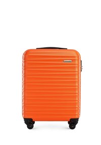 Valise rigide orange avec une texture nervurée, surface lisse, poignée rétractable et quatre roues noires pour la mobilité.