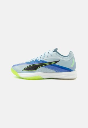 Baskets de sport bleu clair avec logo noir et vert néon, accents bleus, semelle blanche et semelle extérieure vert néon, montrées de profil.