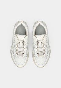 White athletic sneakers with textured fabric, mesh accents, lace-up design, and cushioned insoles, featuring a subtle geometric pattern.