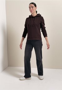 Haut à capuche marron avec cordons, pantalon noir, baskets blanches. Design simple ; texture douce ; coupe décontractée ; sans motifs ni accents visibles.