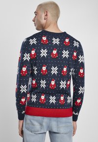 Pull marin avec motifs rouges et blancs de Père Noël et de flocons de neige, ourlet côtelé rouge et encolure ronde, fabriqué en matière tricotée.