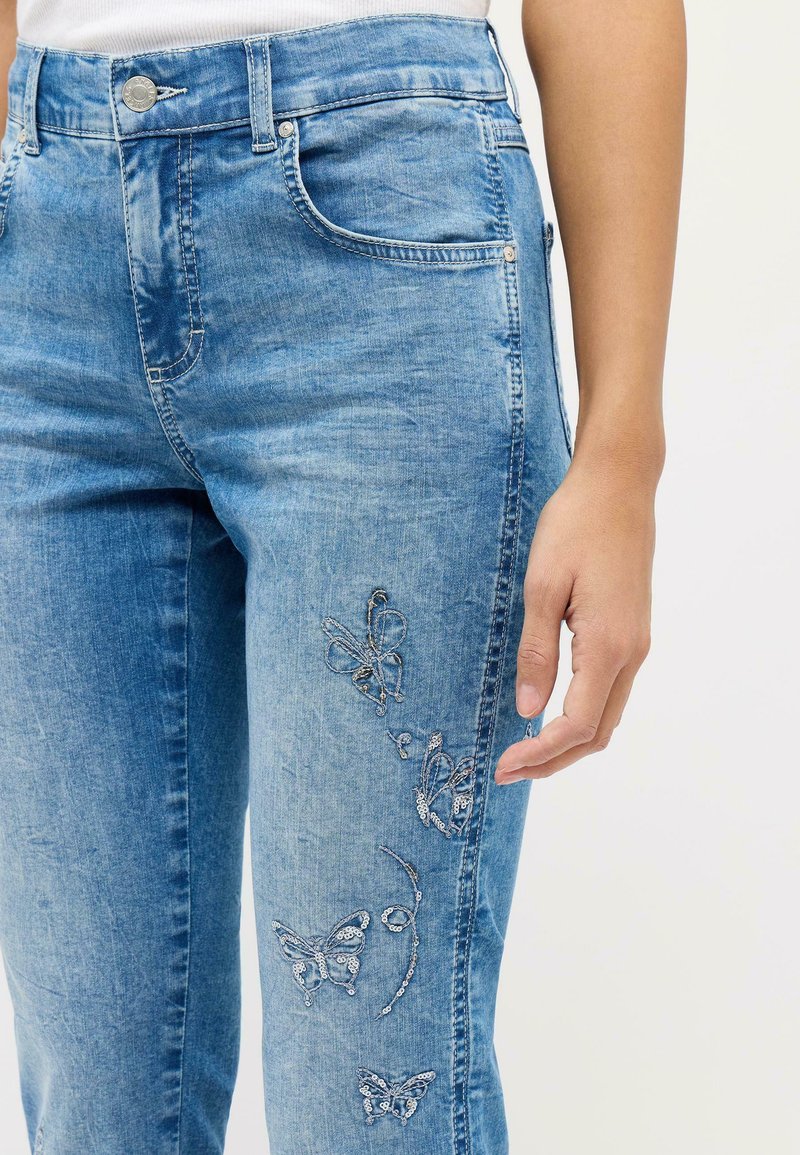 Helle blaue Jeans aus Denim mit Schmetterlingsstickerei an der Seite, im Fünf-Taschen-Stil und einer figurbetonten Silhouette.