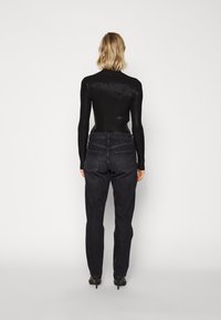 Musta ribbine pitkähihais toppi yhdistettynä tummiin farkkuihin. Slim fit -mallinen, jossa on tavalliset taskut klassisessa suorassa leikkauksessa. Silkkinen pinta ja tarkasti määritellyt saumat.