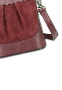 Bordeaux leren en suède handtas met een afneembare schouderband, met een klein Italiaans vlaggetje eraan, op een witte achtergrond.