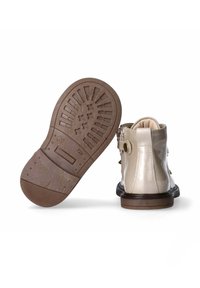 Stivaletti alla caviglia in pelle patent beige con suola in gomma marrone, dotati di una fibbia decorativa e di una morbida fodera. Suola testurizzata per una migliore aderenza.