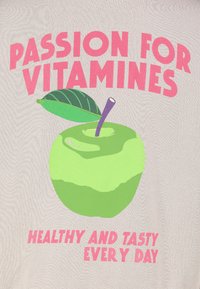 Helle T-Shirt mit pinkem Text. Grafik eines grünen Apfels mit einem Blatt, begleitet von "LEIDENSCHAFT FÜR VITAMINE" und "GESUND UND LECKER JEDEN TAG."