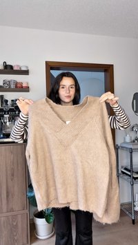 Beige överdimensionerad stickad tröja med bred V-ringning, texturerat tyg och ribbad kant. Har en lös passform och mjukt utseende.