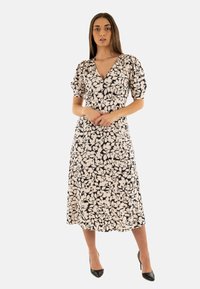 Abito midi floreale in beige e nero, con scollatura a V profonda e maniche a sbuffo. Tessuto morbido con una texture setosa e una silhouette fluida.