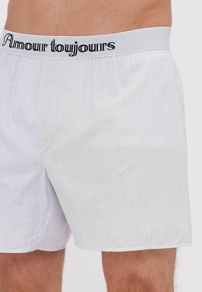 Striped cotton boxers with an elastic waistband featuring "Amour toujours" text. The fabric is soft with a subtle texture in blue and white.
