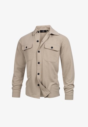 Chemise en flanelle beige avec un col, deux poches avant et des boutons noirs. Tissu texturé avec une coupe décontractée et des manches longues.