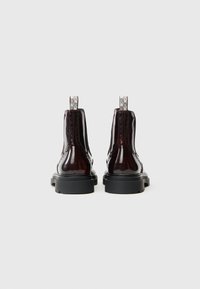 Stivaletti alla caviglia in pelle patent nera con lati testurizzati, linguette per il tiraggio e suole in gomma spesse. Massima attenzione al design elegante e alla finitura lucida.