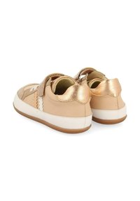 Baskets en cuir beige avec des accents dorés, des bandes auto-agrippantes et des semelles en caoutchouc blanches. Détails texturés sur les côtés et arrière lisse.