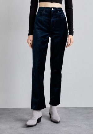 Navy blue velvet wide-leg pants with a high waist, featuring a button closure and front pockets. Paired with gray heeled ankle boots.