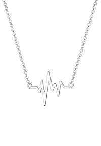 Collier en argent avec un pendentif en forme de battement de cœur sur une fine chaîne, sur fond blanc.