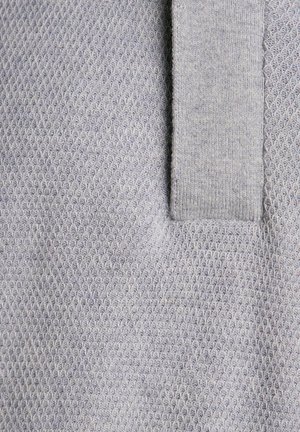 Szary dzianinowy materiał z fakturowanym, plasterkowym wzorem oraz gładkim, jednolitym kołnierzem. Materiał wydaje się miękki i lekki.