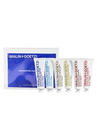 Fünf weiße Tuben mit Hautpflegeprodukten, die farbige Etiketten in Blau, Gelb, Rot und Grün haben, verpackt in einer klaren Tasche mit einem blauen Design.