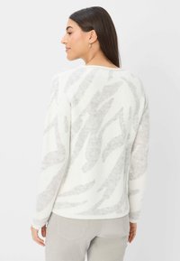 Cremfarbener Pullover mit einem strukturierten Muster in Hellgrau. Rundhalsausschnitt und lange Ärmel, mit einem gerippten Saum. Weiches Strickmaterial.