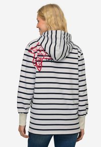 Sudadera a rayas en blanco y azul marino, con un diseño gráfico rojo en la parte posterior, con capucha y puños elásticos. Tejido suave con un corte holgado.