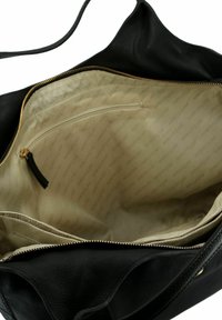 Interieur van een zwarte leren handtas, met een beige voering met herhaald merkteken, een vak met ritssluiting en een ritssluiting bovenaan.