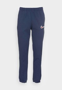 Pantalons de survêtement bleu marine en tissu doux avec une taille élastique et des chevilles resserrées. Présente un petit logo Nike rouge et blanc sur le côté gauche.