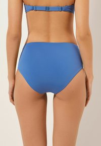 Höga blå bikiniunderdelar gjorda av slät tyg, med en minimalistisk design och inga synliga mönster eller detaljer.