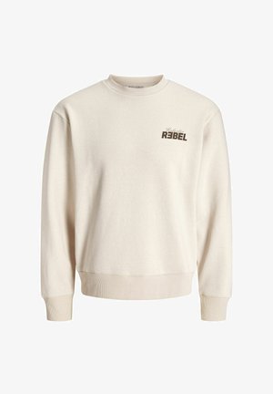 Beige väriin oleva pyöreäkauluksinen svetari, jossa on resorit hihansuissa ja helmassa. Lisäksi ylävasemman rinnan kohdalla on tummanruskealla tekstillä teksti "Selective REBEL".