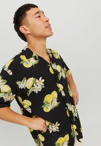 Camicetta nera a maniche corte con motivo di limoni gialli e fiori, davanti con bottoni e vestibilità rilassata, realizzata in tessuto leggero.