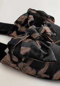 Schwarze Stoff-Sandalen mit flachem Sohlen und einer strukturierten Schleifenakzent im Blumenmuster in sanften Brauntönen für zusätzlichen Komfort.