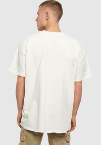 Hvid kortærmet T-shirt med afslappet pasform og rund halsudskæring. Glat stof uden synlige mønstre eller grafik. Back view vises.