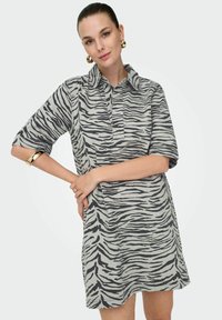Robe chemise à manches courtes en gris clair avec des rayures zèbre noires, dotée d'un col et d'une coupe décontractée. Tissu doux avec une texture lisse.