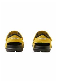 Sandales jaunes avec des accents noirs, présentant un design ouvert à l'arrière et des sangles velcro. Nom de la marque "reima" affiché sur le côté.
