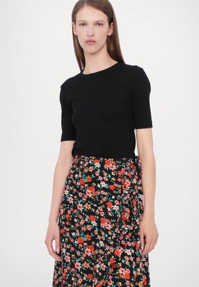 Svart kortärmad topp matchad med en svart blommig omslagskjol som har mönster i röd, rosa och grön färg, mjukt tyg och en sidoknytdetalj.
