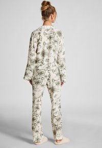 Bloemenprint pyjama set in roomkleur en groen, met een collared lange mouw top en bijpassende broek met een zachte textuur. Slippers inbegrepen.