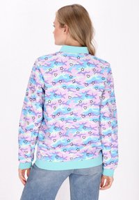 Giacca bomber colorata con un motivo camouflage pastello arricchito da stelle e cuori, realizzata in tessuto morbido, con polsini e colletto a costine.