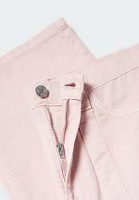 Pantalones de mezclilla rosa claro con cierre de cremallera y botón de metal. Tienen un corte recto y detalles de costura visibles.