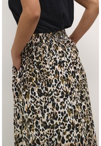 Jupe à motif léopard en tissu léger ; taille élastique, poches latérales et différentes nuances de beige, noir et vert olive.