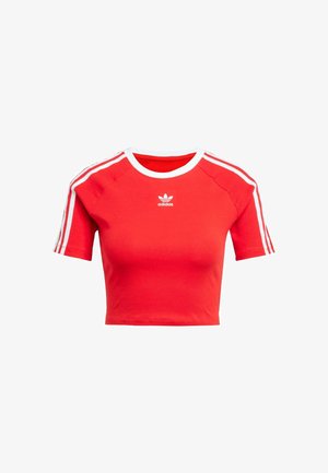 Red cropped t-shirt made of cotton, features short sleeves with white stripes and a white collar, and has the Adidas logo in white on the front.