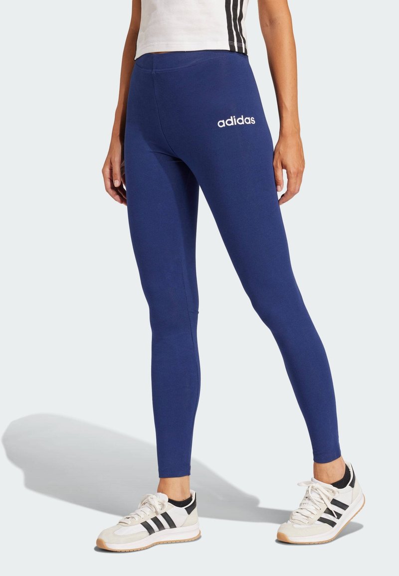 Marina leggings i stretchtyg, med en åtsittande design och vit "adidas"-logotyp på vänster höft, kompletterade med sportskor.