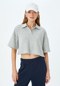 Grå cropped polo skjorte med krave, to knapper og korte ærmer, parret med navy bukser. Tekstureret stof; casual pasform.