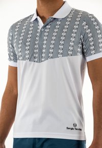 Polo shirt con una parte superiore grigia chiara con motivo che presenta loghi ripetuti, una sezione inferiore bianca e un colletto a contrasto.