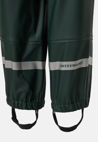 Pantalon imperméable vert foncé avec des bandes réfléchissantes près des bas, ourlets élastiqués, sangles pour les pieds et le nom de la marque Swedemount imprimé.