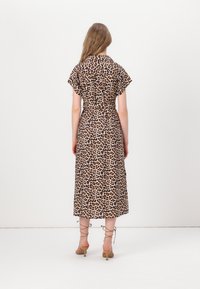Rochie maxi cu imprimeu leopard, cu mâneci scurte, talie strânsă, material ușor și un design fluid. Include sandale cu toc cu curele în jurul gleznei.