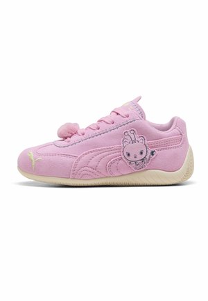 Roze suède kindersneaker met pomponveteraccent, cartoon buitenaards karakterpatch op de zijkant en lichtbeige zool.