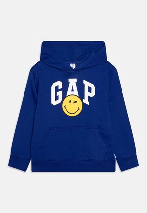 Børneblå hættetrøje med forlomme, hvid "GAP"-tekst og gul blinkende smiley-logo på brystet.