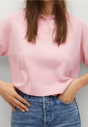 Różowy bawełniany top w stylu polo z plisą na trzy guziki, krótkimi rękawami i prążkowanym dołem, zestawiony z wysokim stanem szortami dżinsowymi.