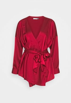 Red satin long-sleeve wrap blouse with deep V-neck and tied waist bow, featuring a slightly asymmetrical hem.