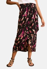 Melna midi svārku ar rozā un krējuma ziedu rakstu, ar savāktu dizainu un šķirbu. Valkāts ar sandālēm.