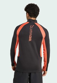 Climacool athletic long-sleeve shirt in black with bright orange accents. Features a high collar and breathable material for ventilation.