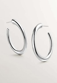 Pendientes de aro de plata con un diseño liso y curvado, que presentan un acabado pulido y un poste fino para un uso seguro.